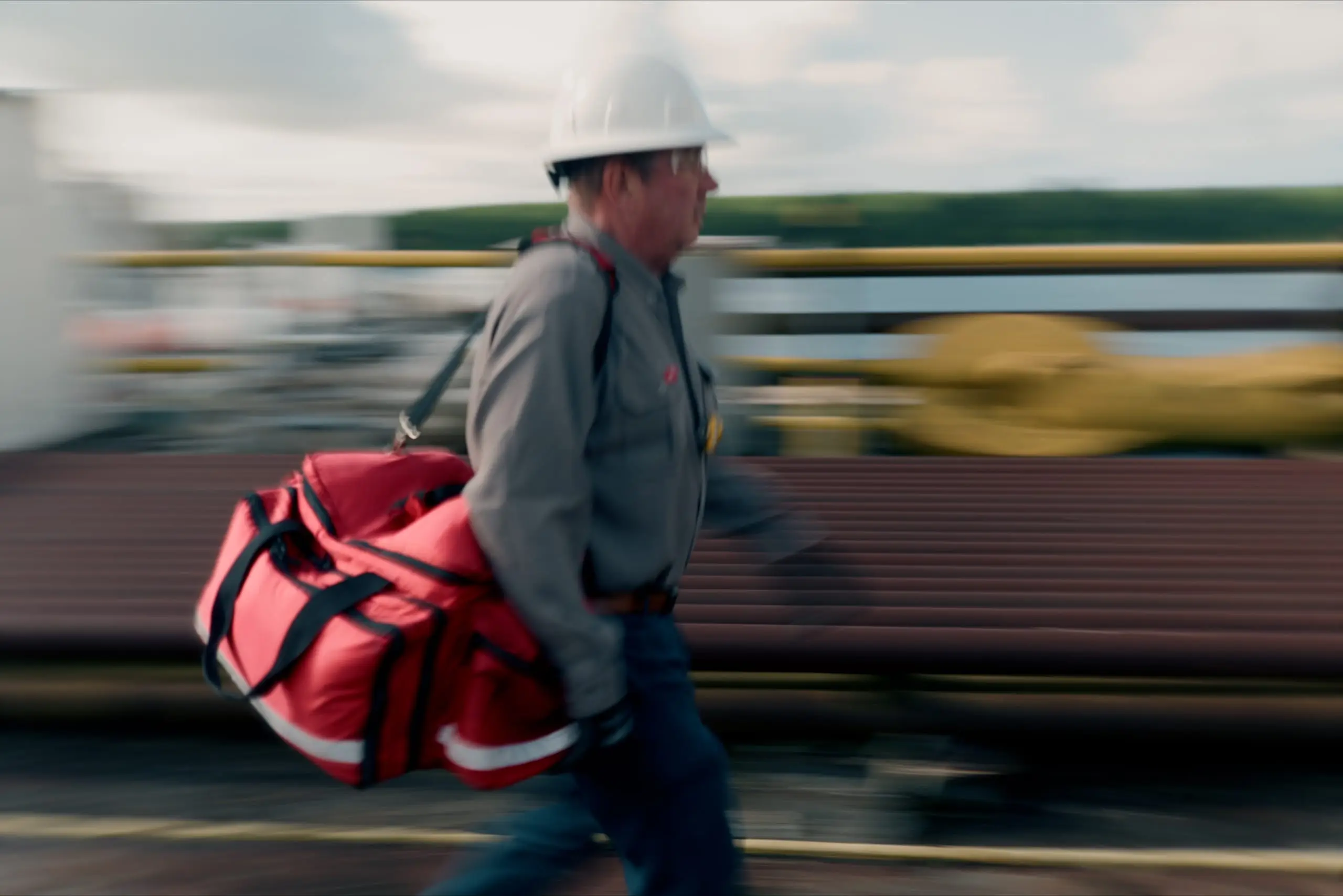 An On Site medic moving with an emergency medical response bag across a rig